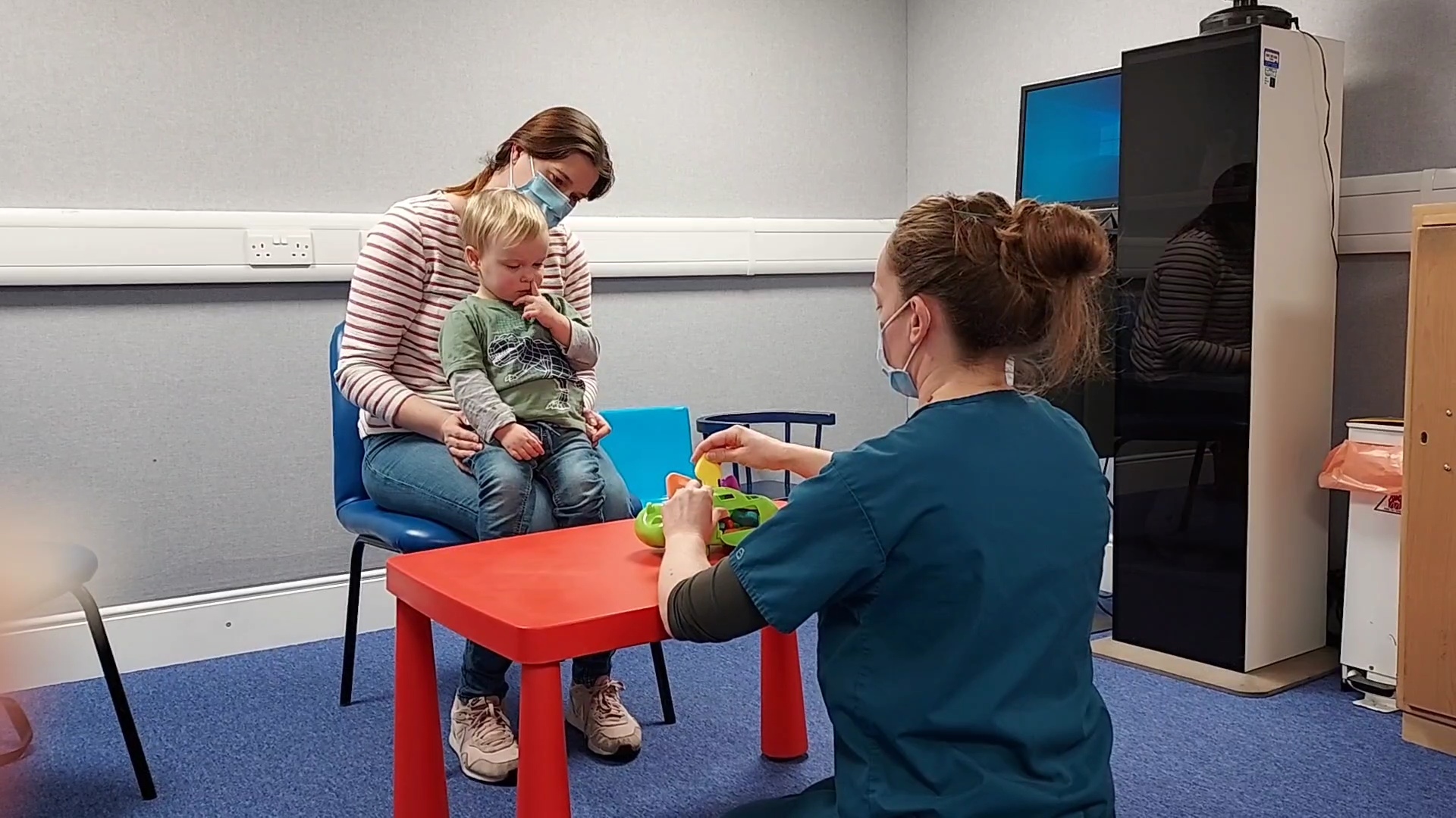 Child sat with mother during audiology assessment