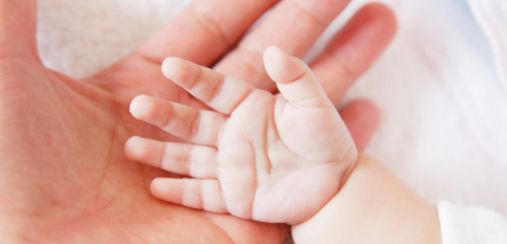 A baby's hand against an adult hand.